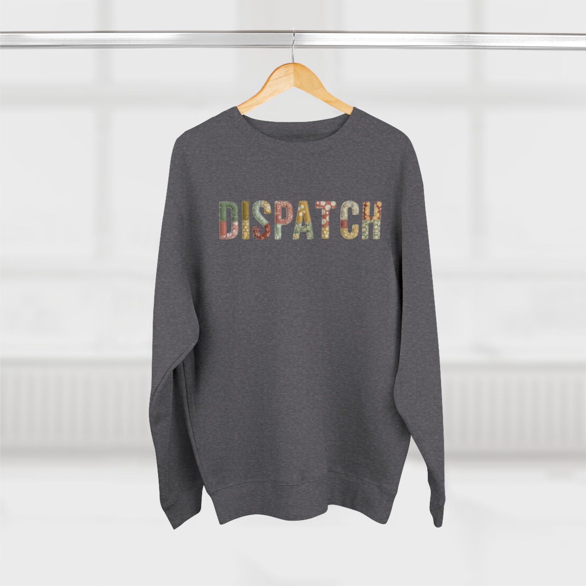 Gray sweatshirt with 'Dispatch' printed on it, hanging on a wooden hanger against a white background.