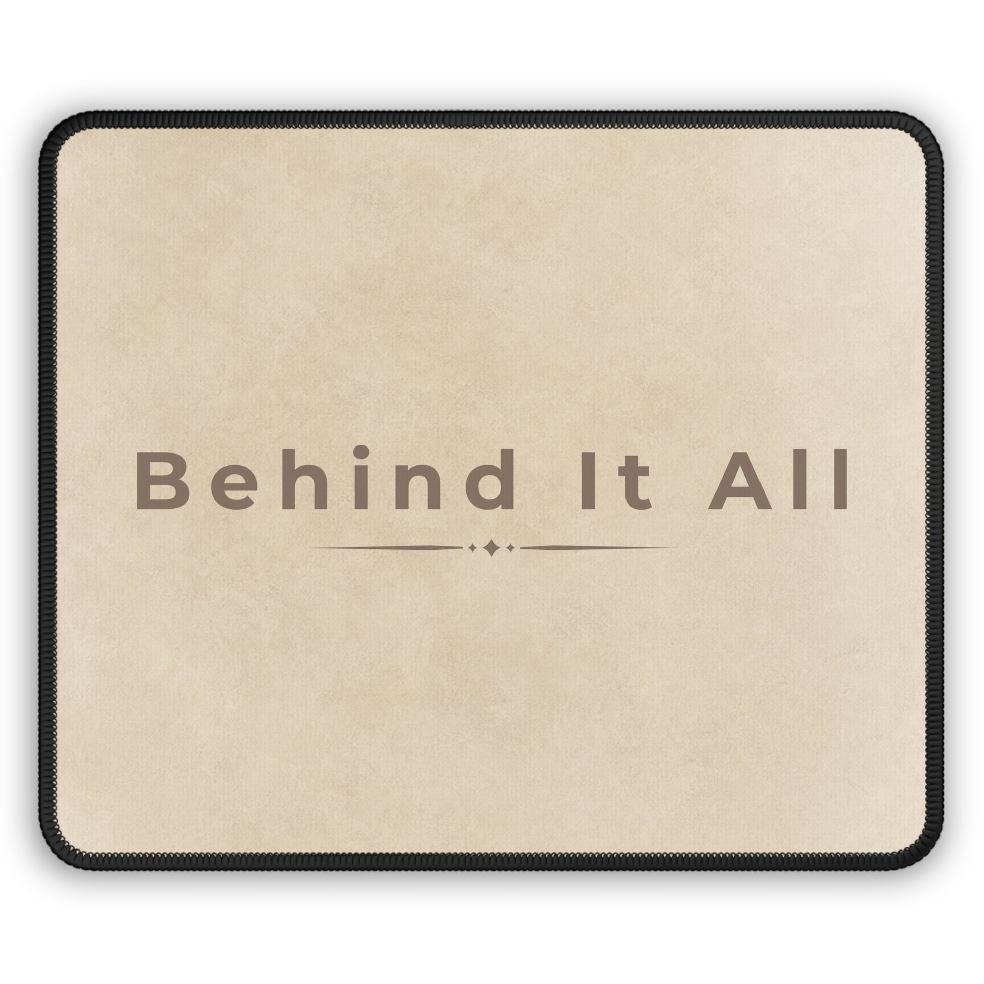 Beige mouse pad with 'Behind It All' text on a white background