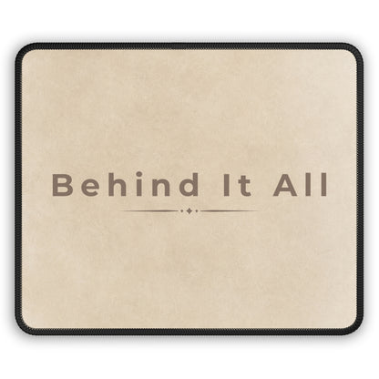 Beige mouse pad with 'Behind It All' text on a white background