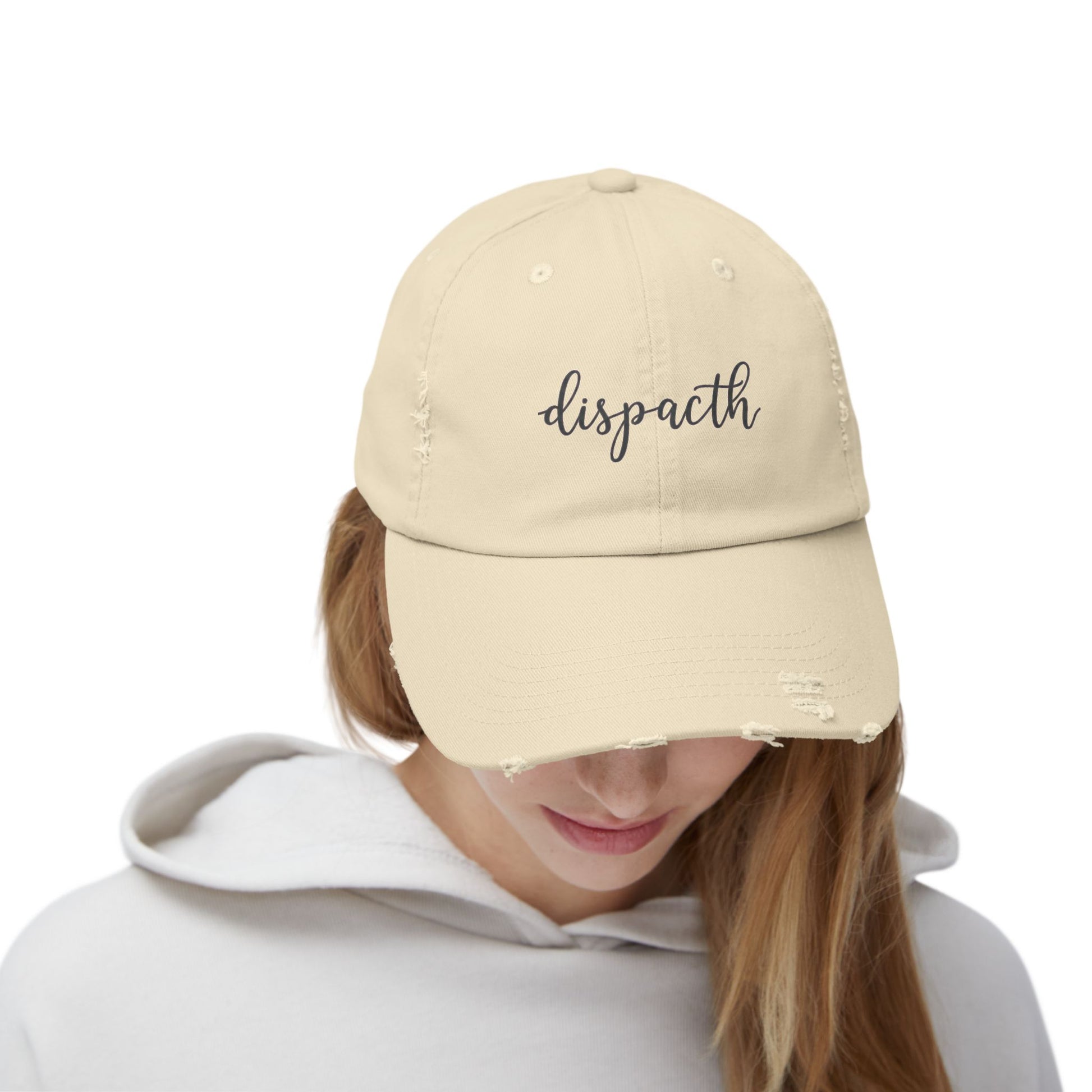Beige cap with embroidered crosses worn by a person on a white background