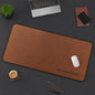 Brown desk mat with 'NO SHORTCUTS' text on a dark surface with office items.