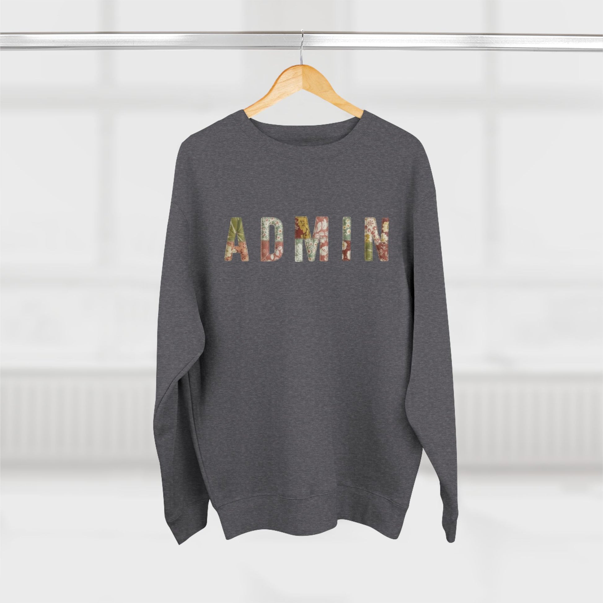 Gray sweatshirt with 'Admin' printed on it, hanging on a wooden hanger against a white background.