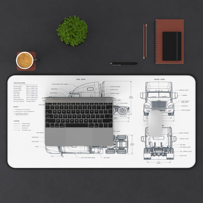 Desk setup with a large desk mat featuring a truck blueprint, laptop, cup, plant, and stationery items on a dark surface.