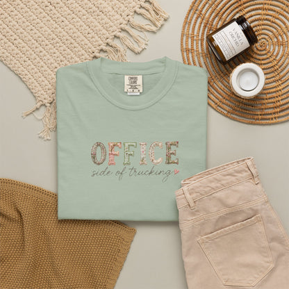 GREEN t-shirt with 'OFFICE SIDE OF TRUCKING' text, beige pants, and decorative items on a light gray surface.