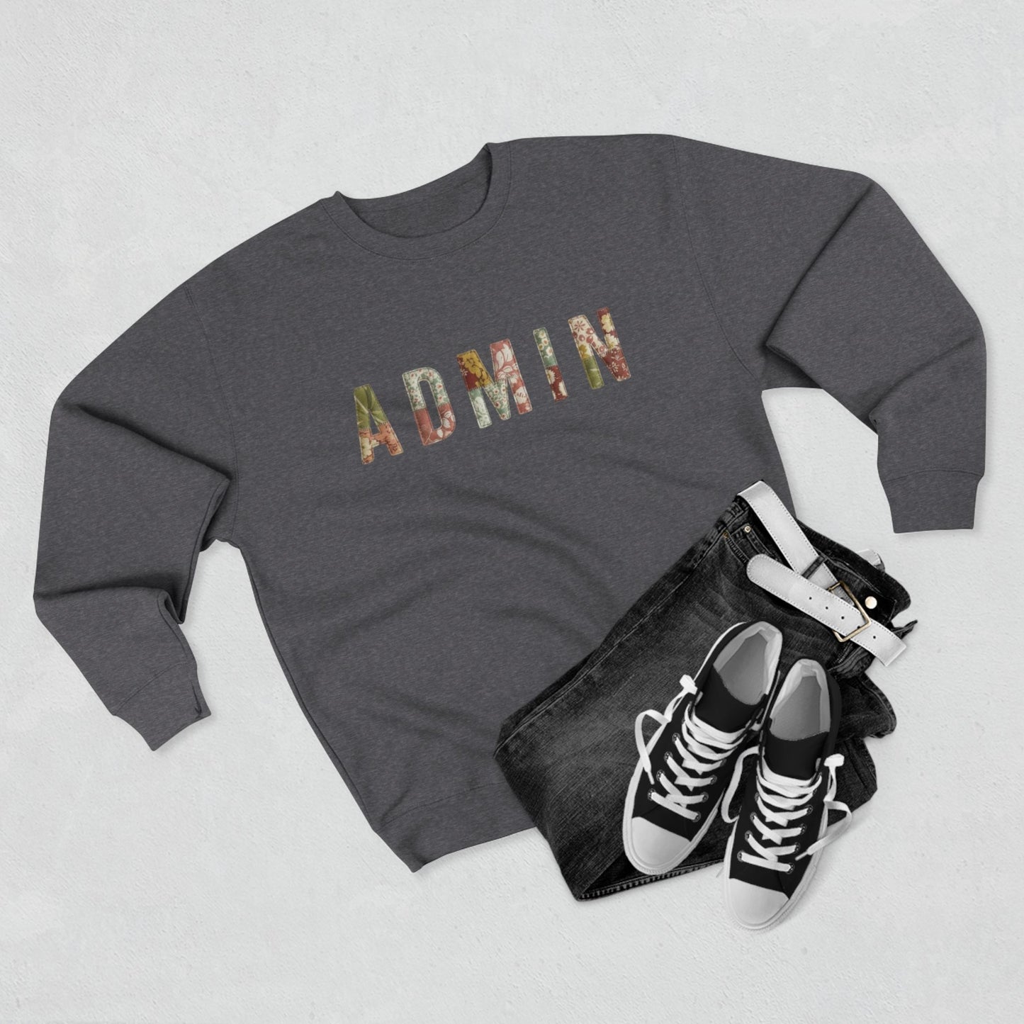 GREY SWEATSHIRT with 'ADMIN' text on a neutral surface with beige pants and decorative items.