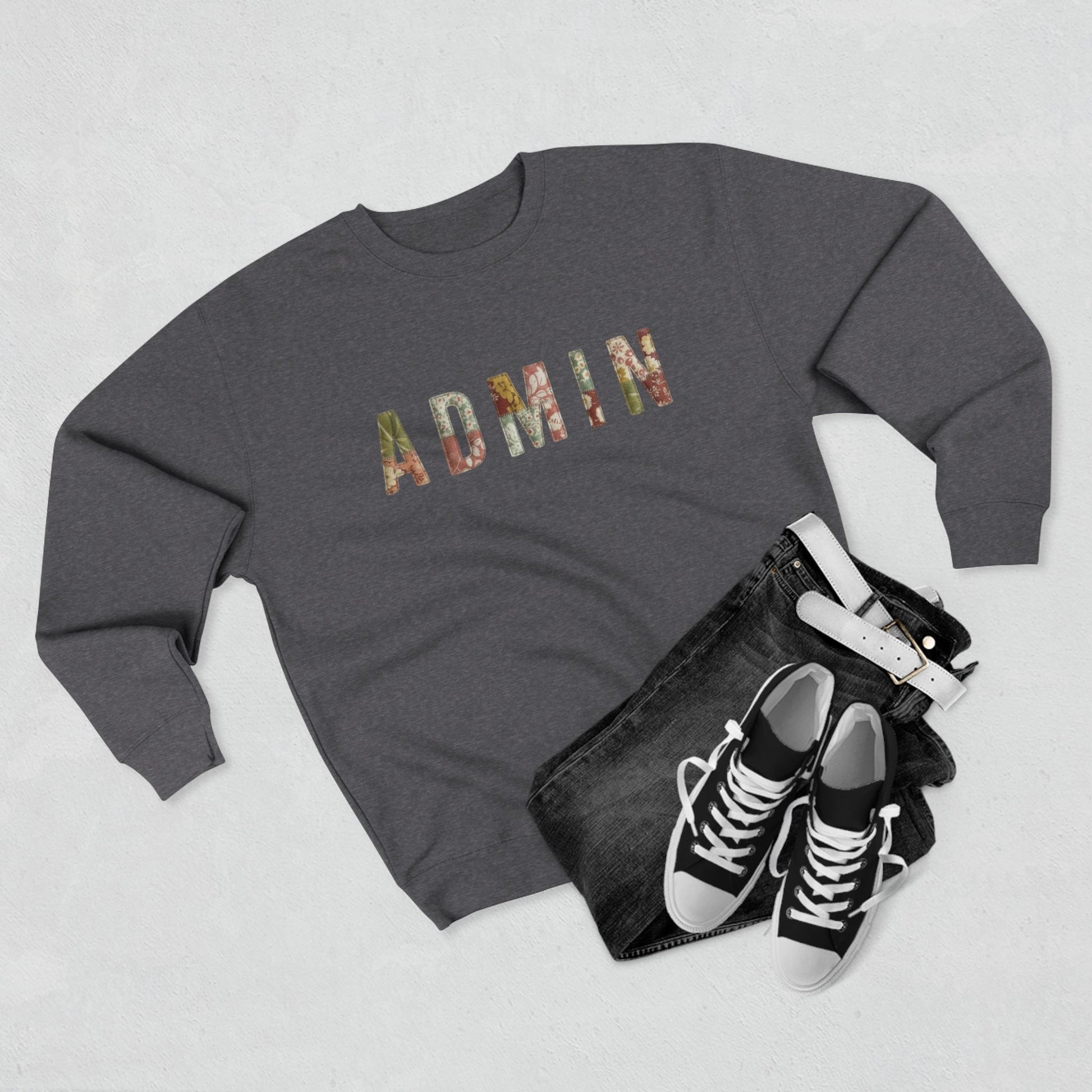 GREY SWEATSHIRT with 'ADMIN' text on a neutral surface with beige pants and decorative items.
