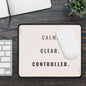 Mouse pad with 'CALM. CLEAR. CONTROLLED.' text on a desk with keyboard and plant