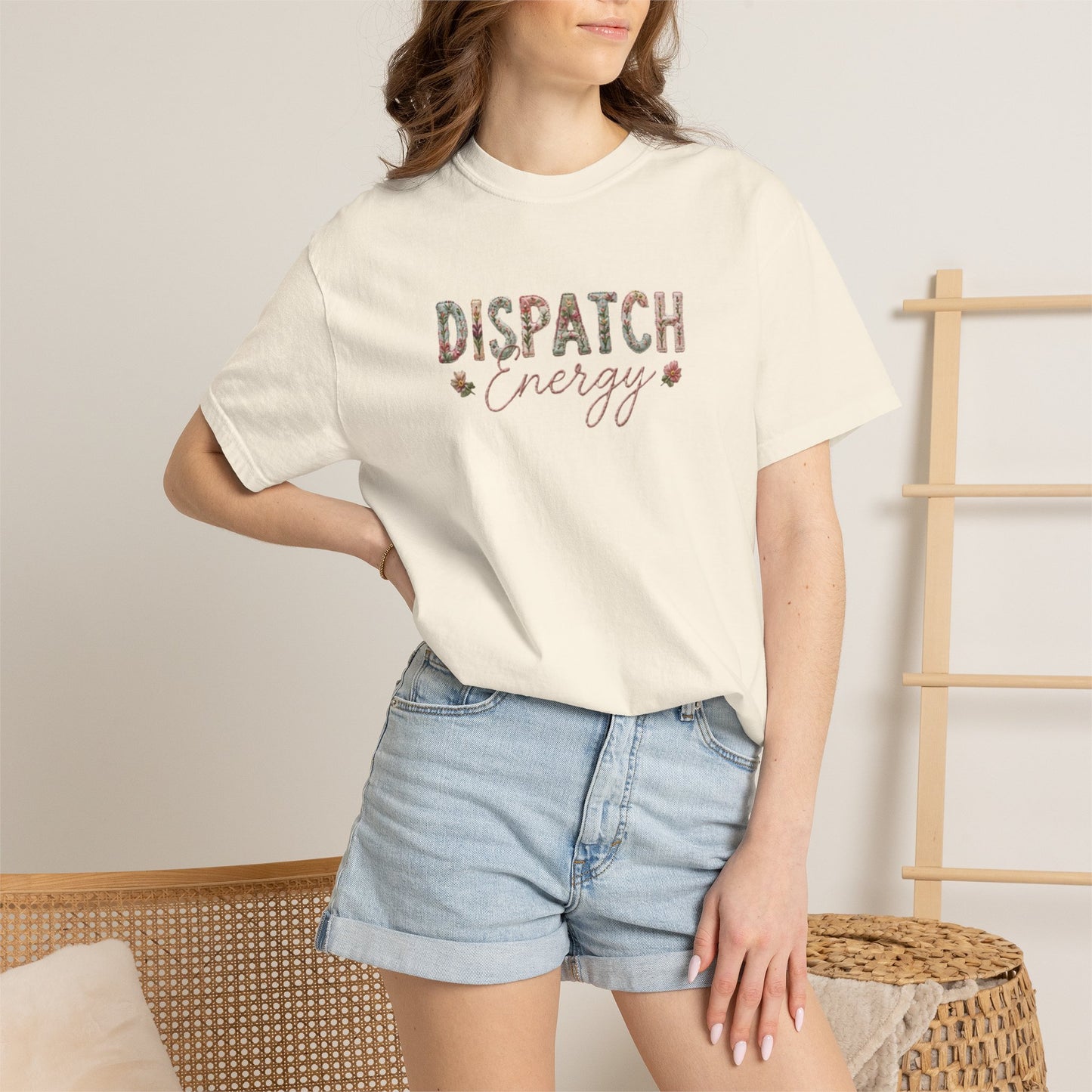 Person wearing a white t-shirt with 'DISPATCH ENERGY' text and denim shorts indoors.