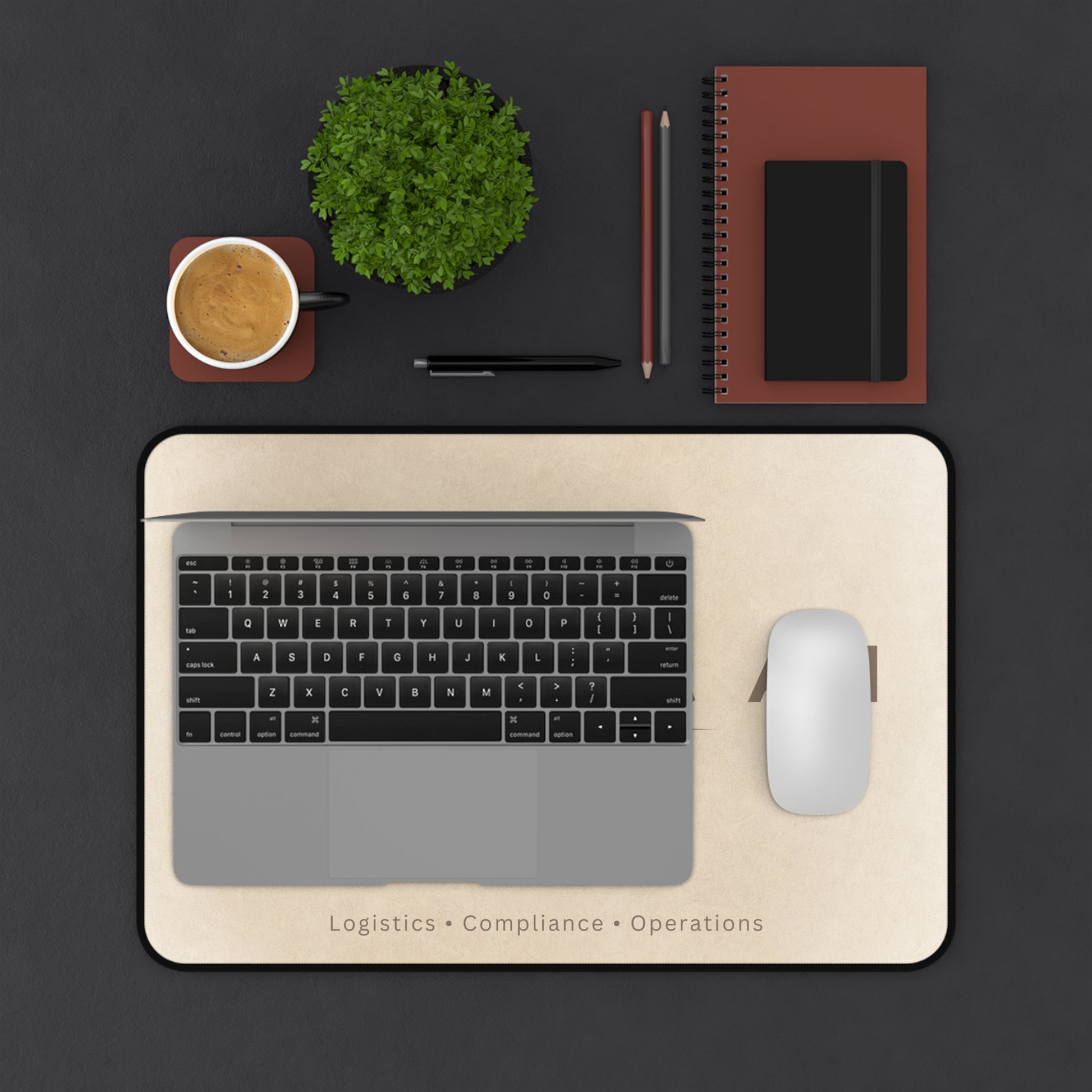 Laptop on a pink marble desk mat with a cup, plant, and stationery items on a black background.