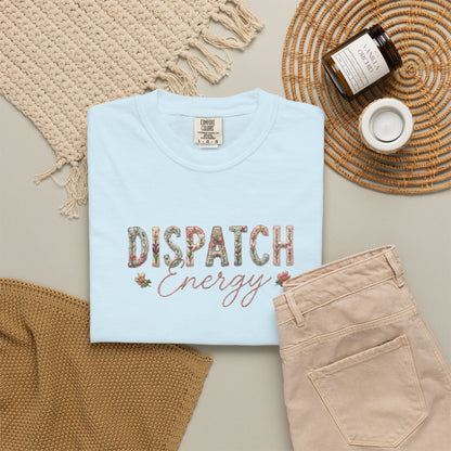 Light blue t-shirt with 'Dispatch Energy' text on a neutral background with beige pants and decorative items.