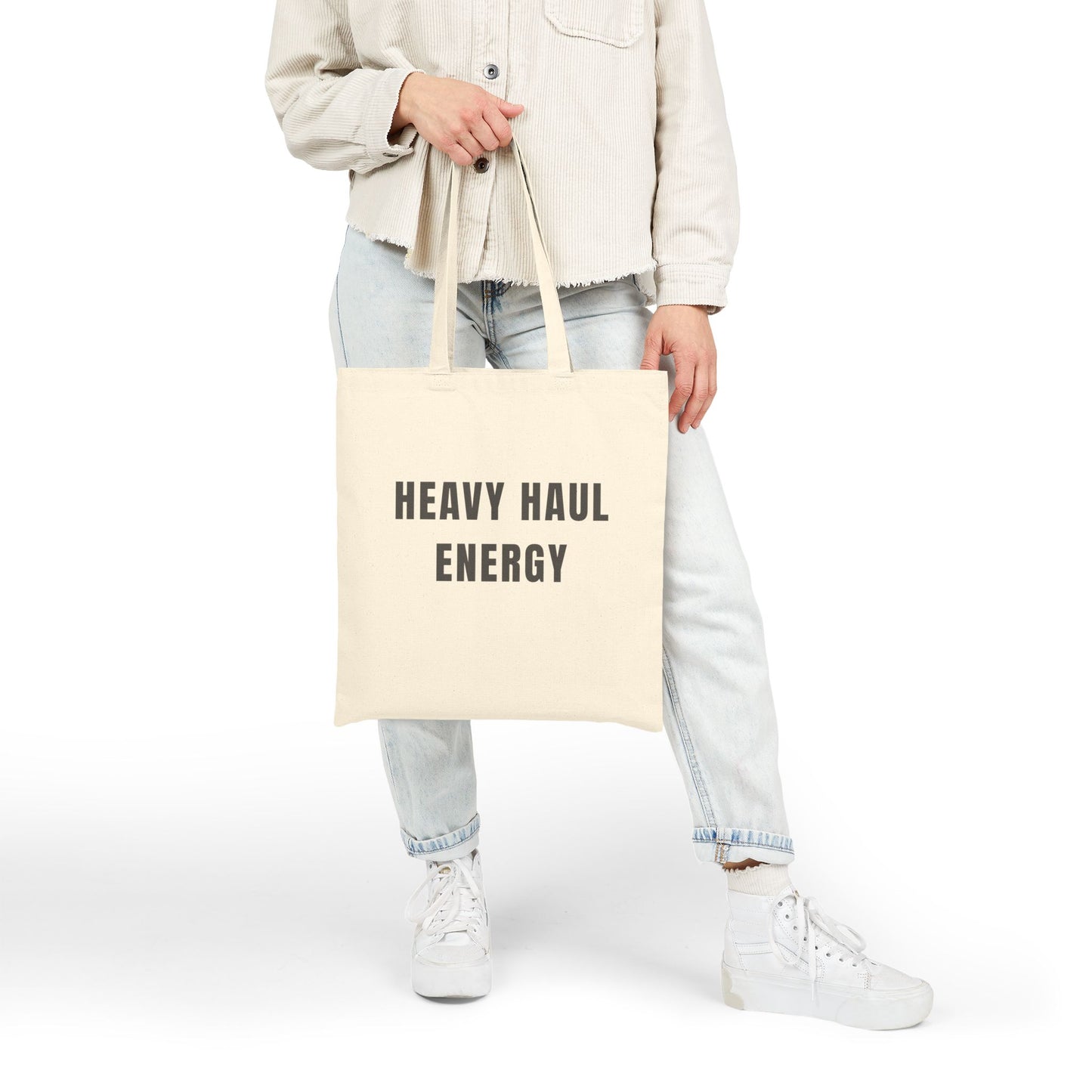 Person holding a tote bag with 'HEAVY HAUL ENERGY' text on a white background