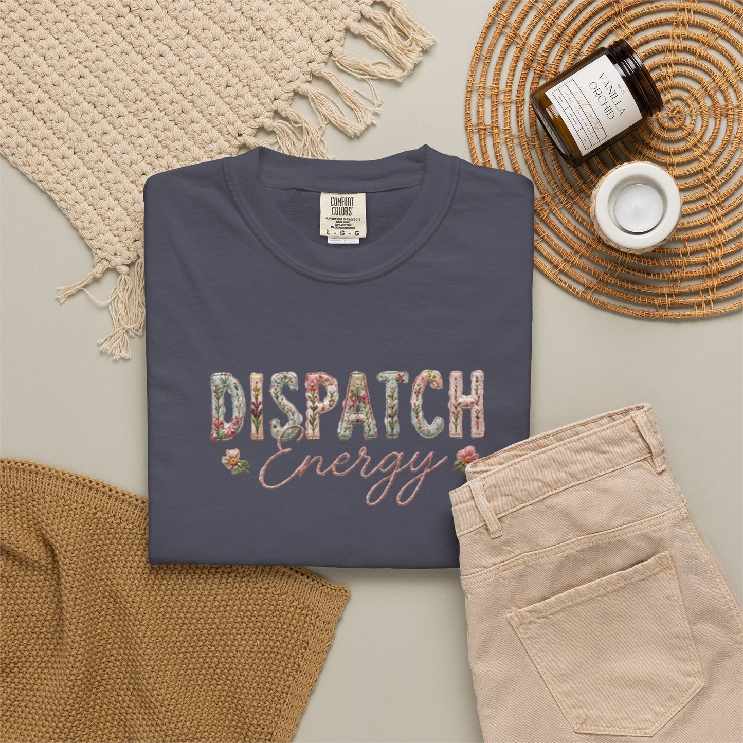 Navy blue t-shirt with 'Dispatch Energy' text on a neutral surface with accessories.