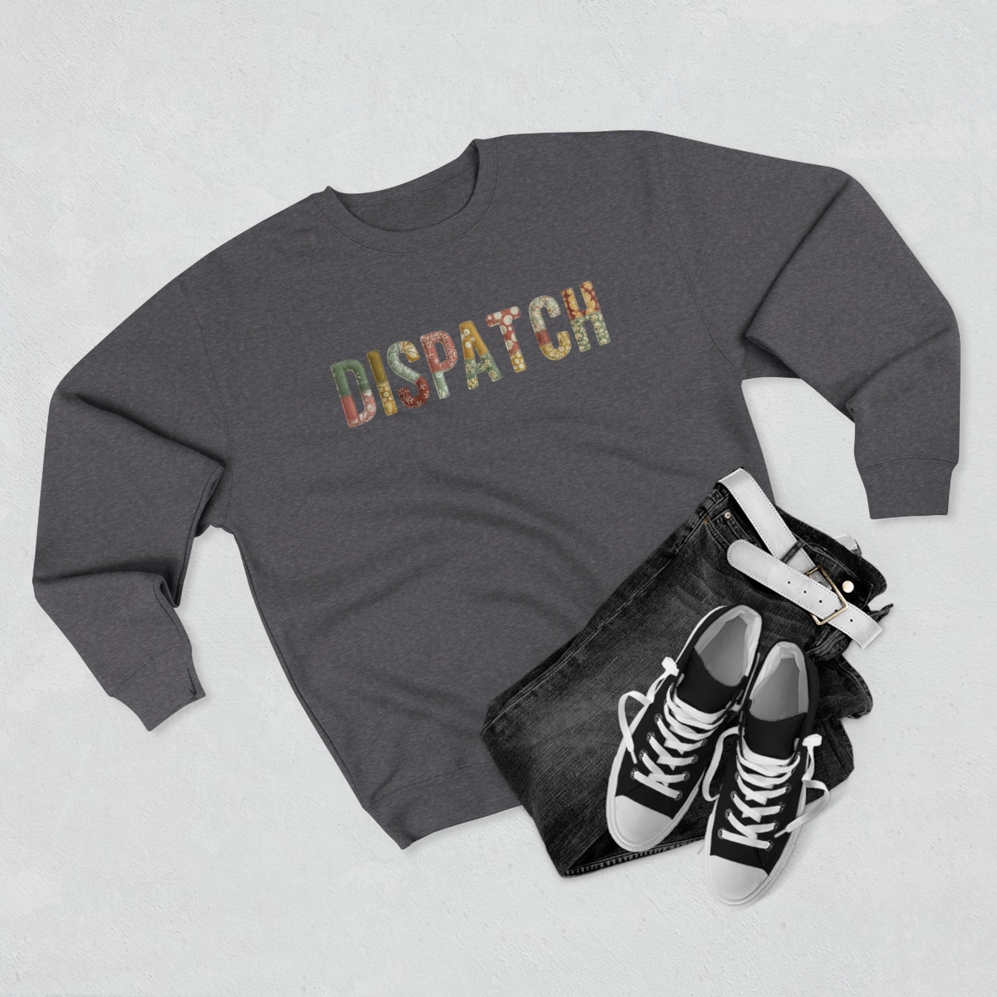 Gray sweatshirt with 'dispatch' design, black jeans, and black sneakers on a light gray background