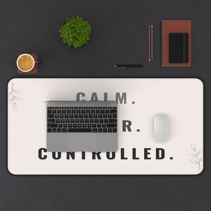 Desk setup with a laptop, mouse, and decor items on a desk mat with text.