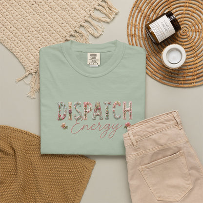Folded mint green t-shirt with 'Dispatch Energy' text on a neutral surface with accessories.