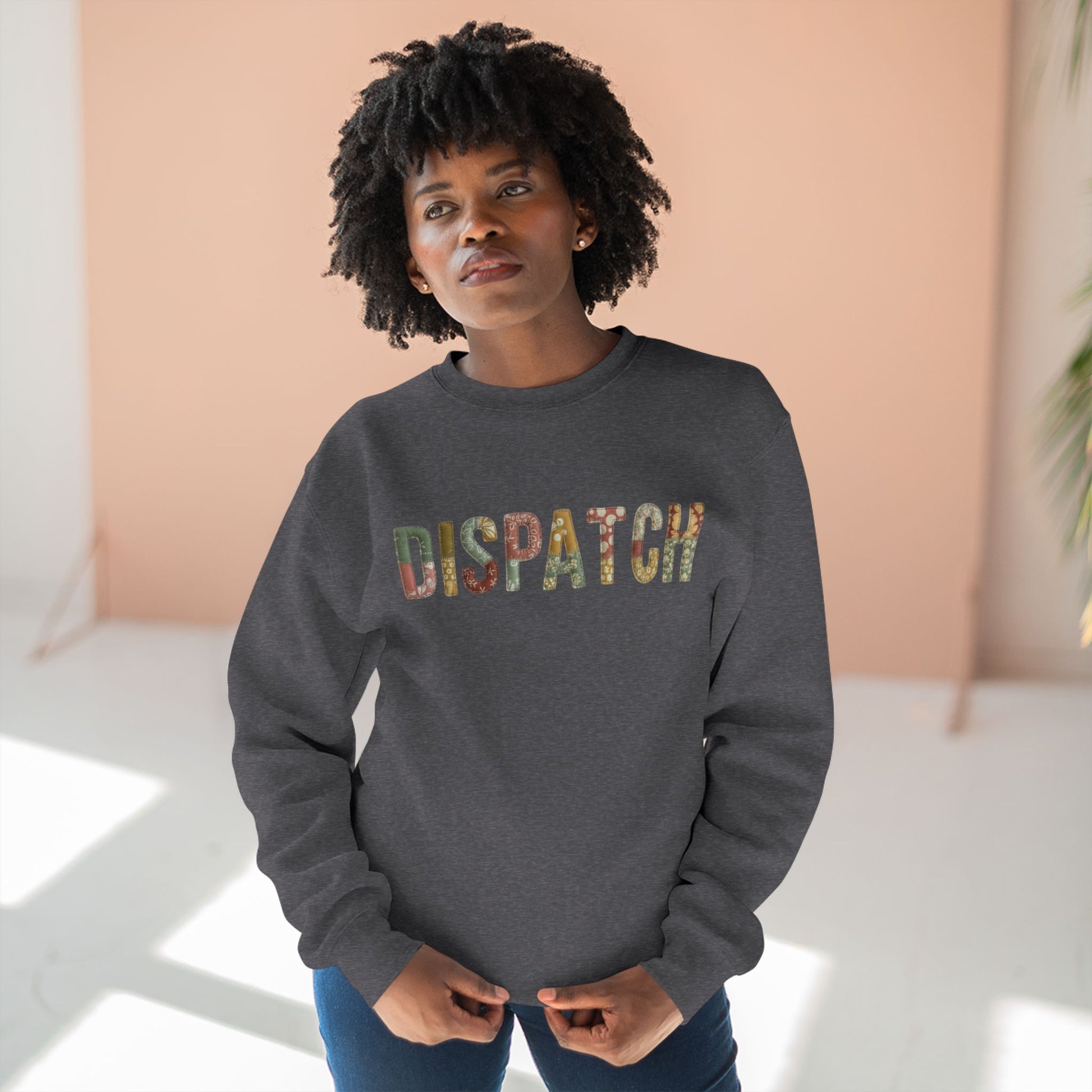 Person wearing a dark gray sweatshirt with 'DISPATCH' printed in colorful letters against a light background.