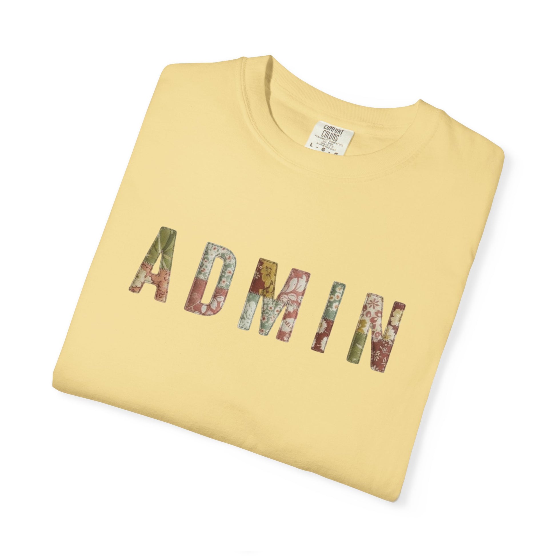 Folded yellow t-shirt with 'ADMIN' printed in colorful letters on a white background