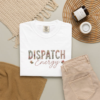 White t-shirt with 'Dispatch Energy' text on a neutral background with beige pants and decorative items.