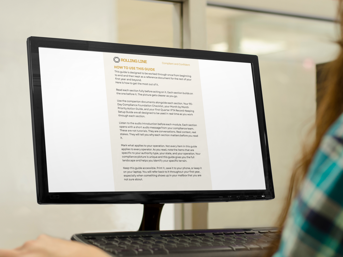 Person using a computer with a document on the screen in an indoor setting