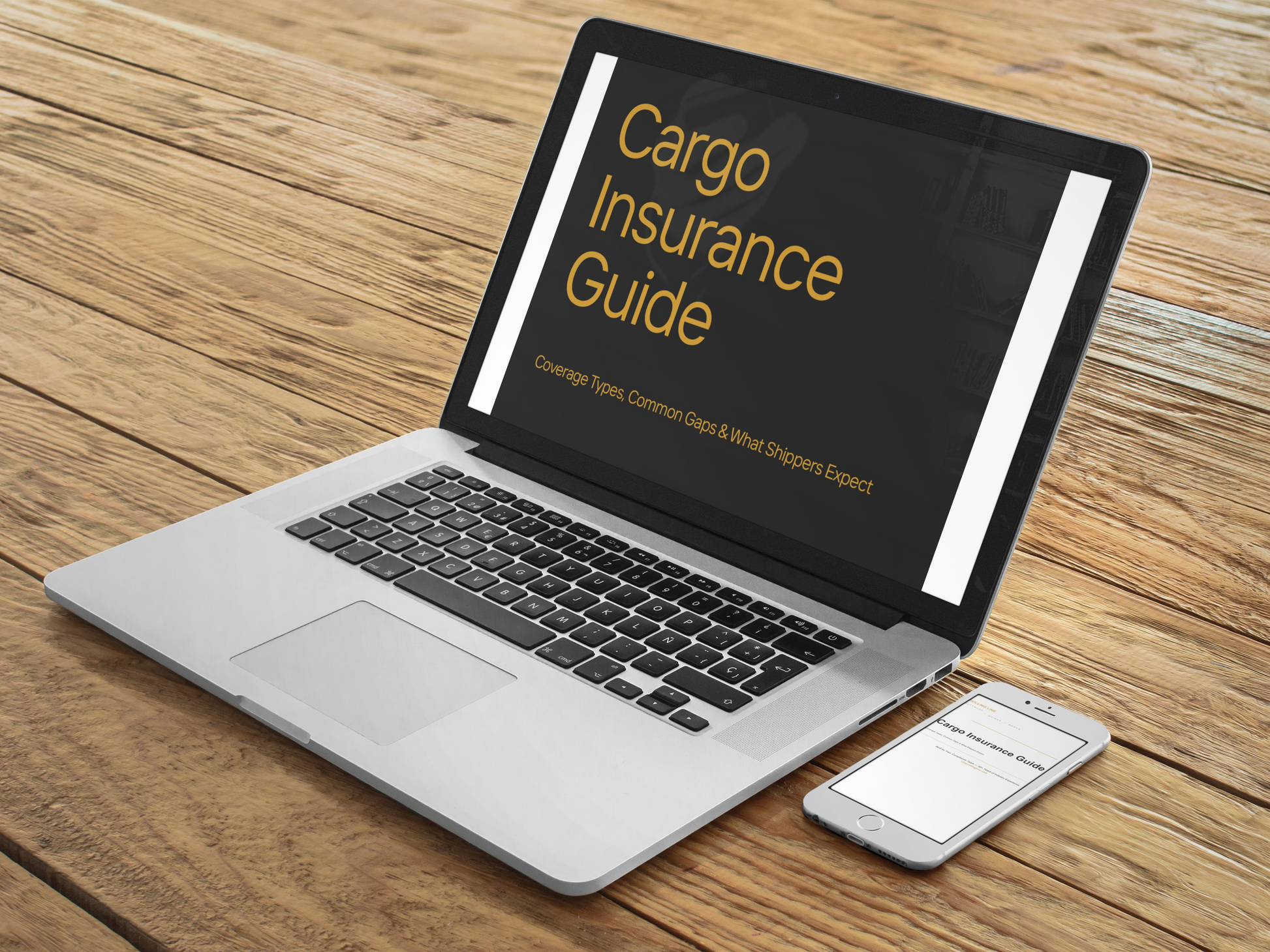 Laptop displaying 'Cargo Insurance Guide' on a wooden surface with a smartphone beside it.