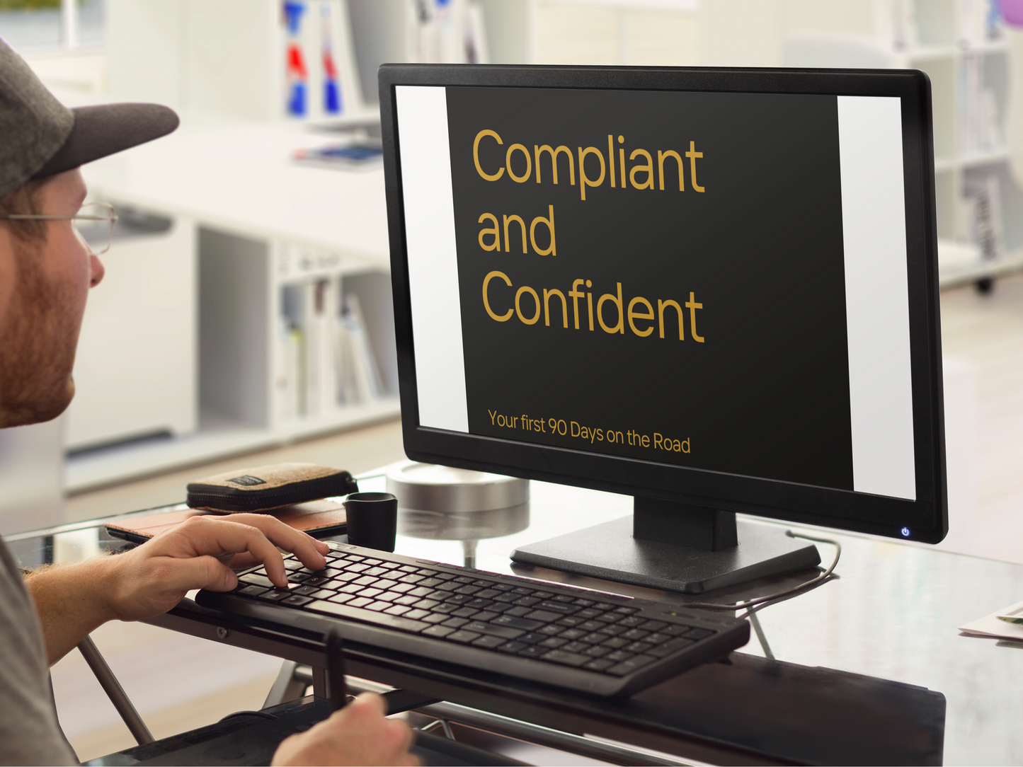 Person using a computer with a screen displaying 'Compliant and Confident' text in an office setting.