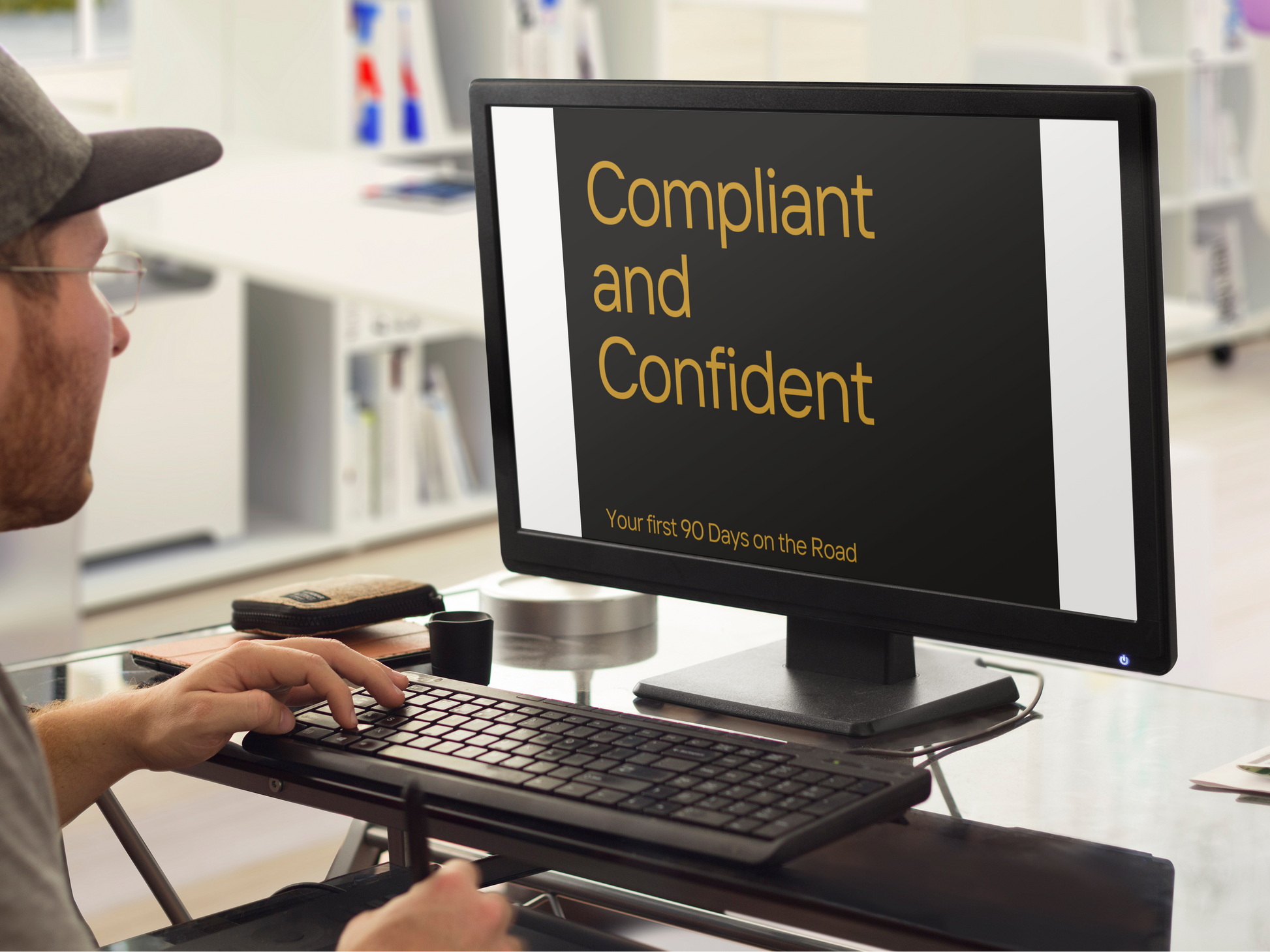 Person using a computer with a screen displaying 'Compliant and Confident' text in an office setting.