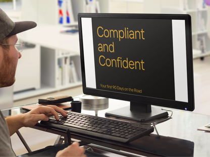 Person using a computer with a screen displaying 'Compliant and Confident' text in an office setting.